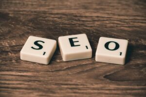 Tuiles de Scrabble avec le mot « SEO » sur une surface en bois. Idéales pour les thèmes de marketing numérique.